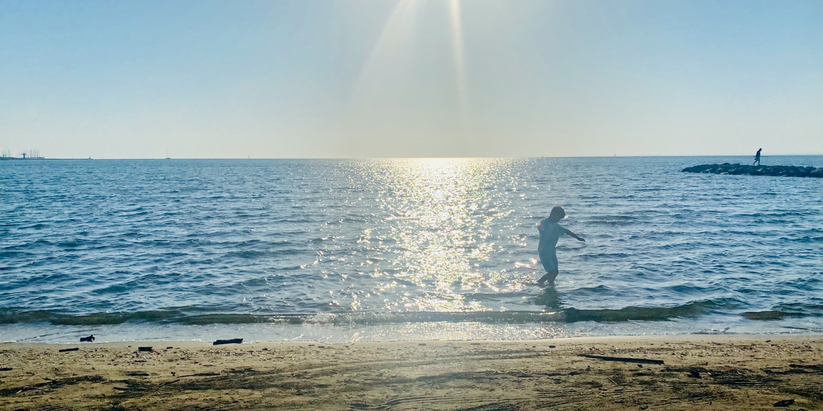 Enfant jouant les pieds dans l'eau en basse saison, Rive Gauche le Grau-du-Roi
