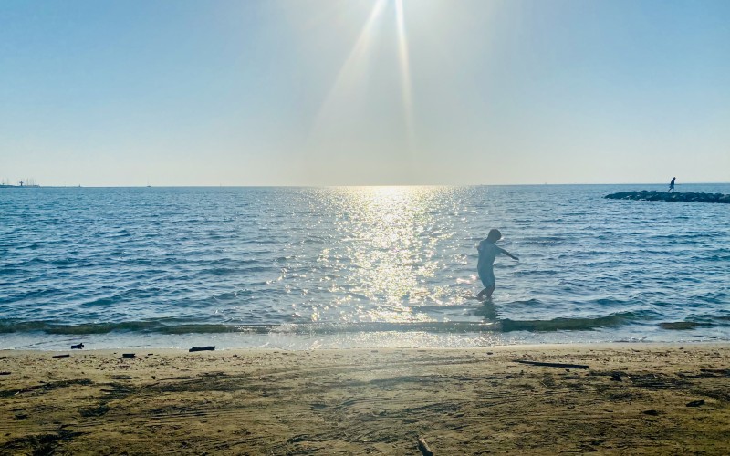 Enfant jouant les pieds dans l'eau en basse saison, Rive Gauche le Grau-du-Roi