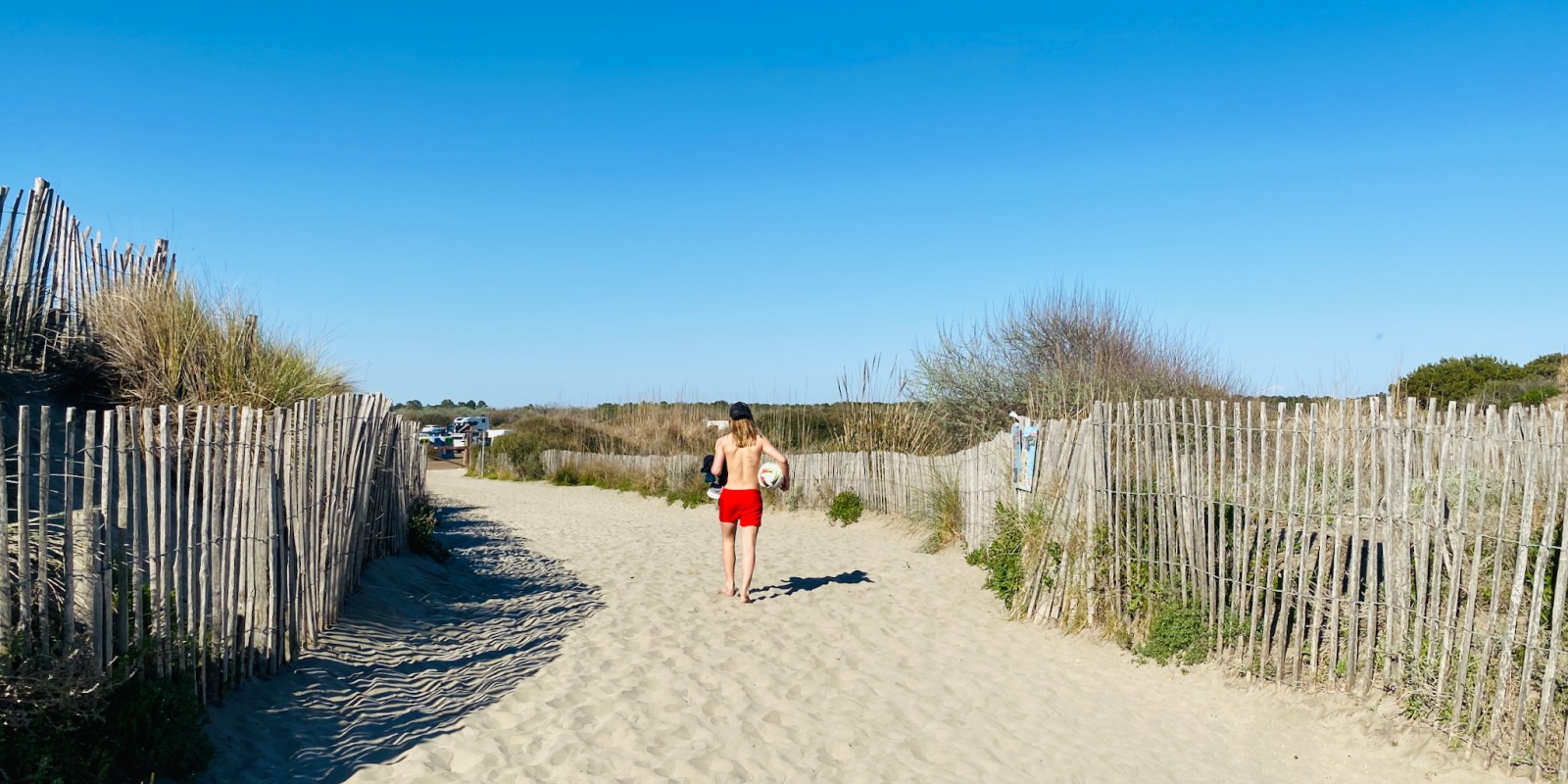 Jeune adolescent revenant de la plage avec son ballon de foot